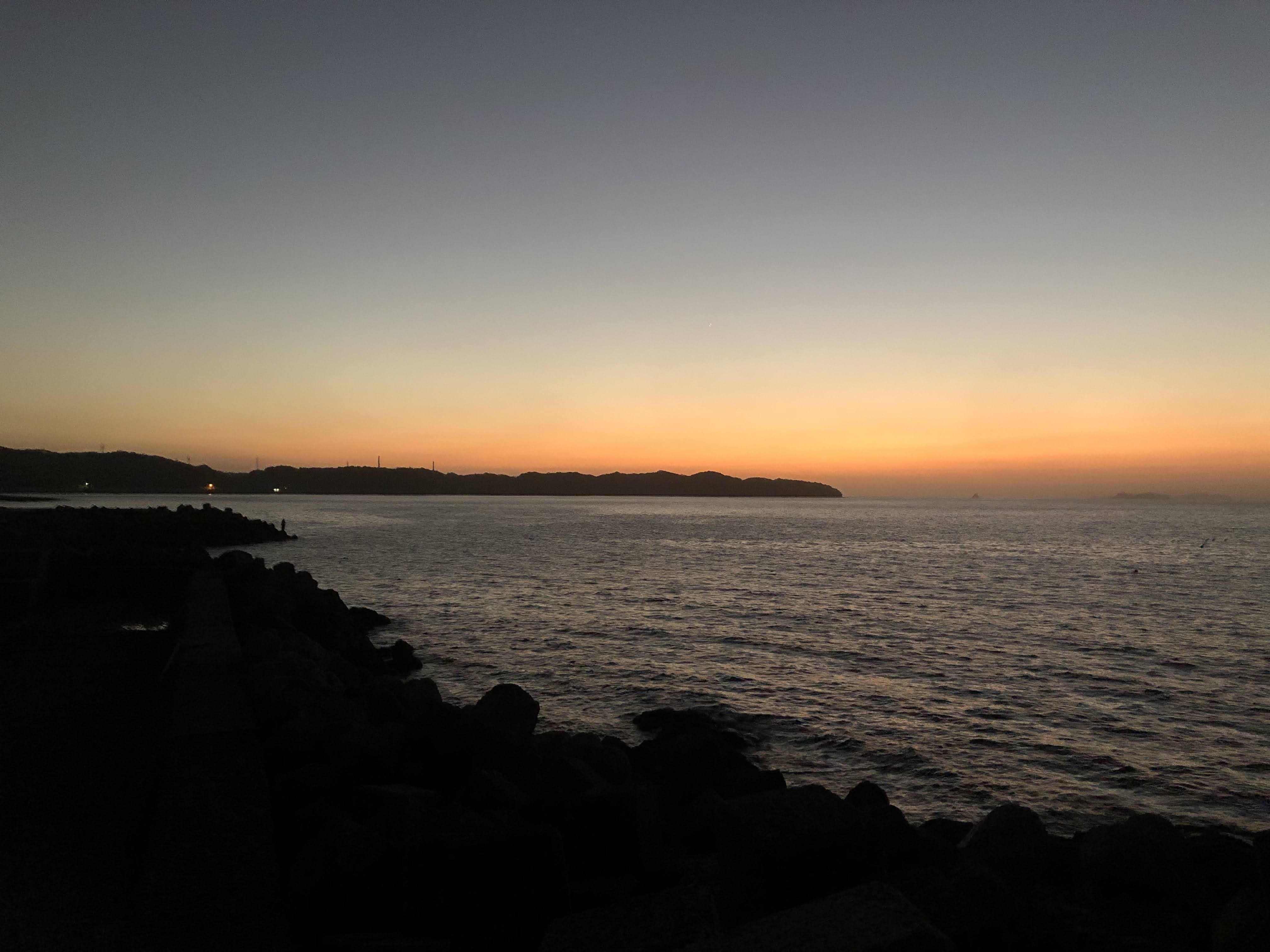 夕暮れの堤防で釣りをする風景